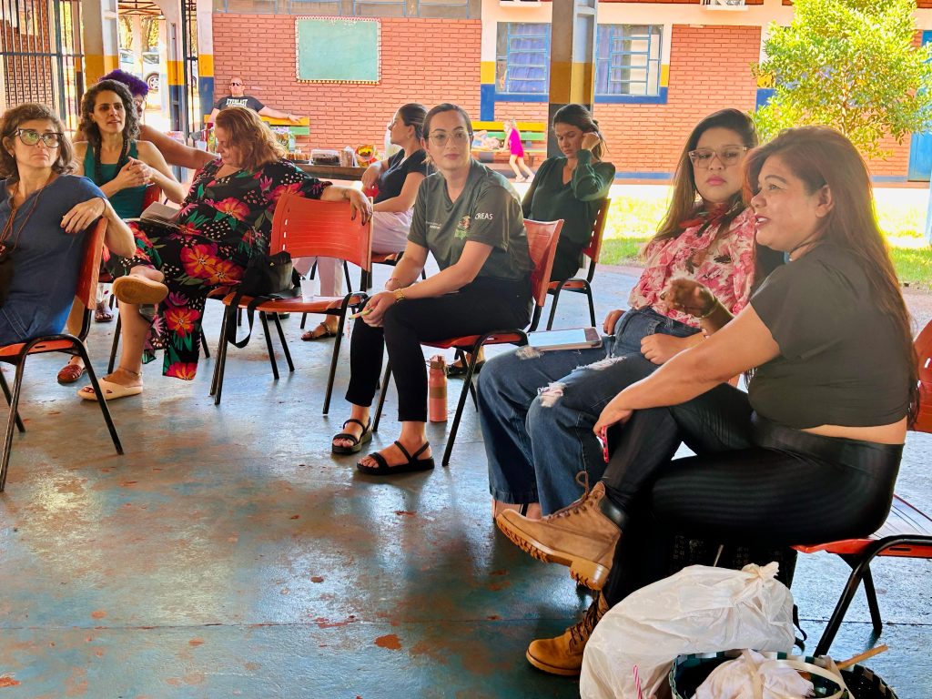 Mulheres sentadas em cadeiras em meia-lua conversando sobre a realidade da violência contra indígenas. 