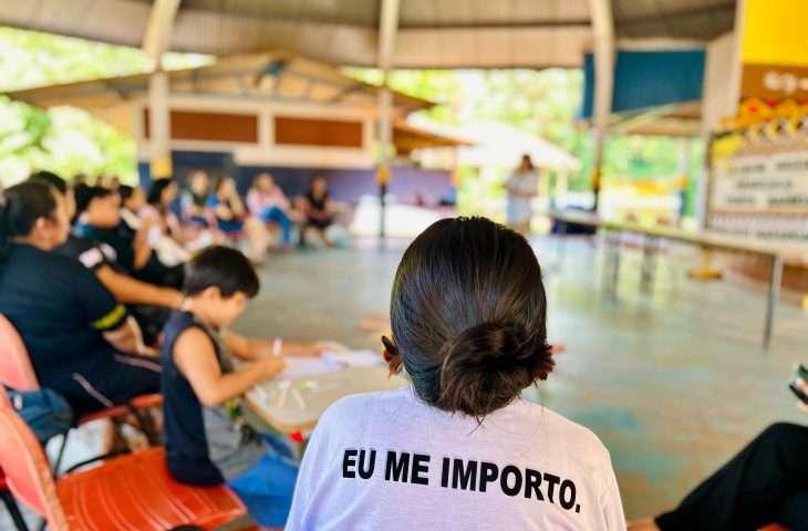 Mulher de costas com camiseta escrita "Eu me importo" durante encontro de mulheres indígenas.