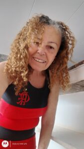 Beneficiária Quitéria Bernado da Silva usando uma camiseta regata do Flamengo.
